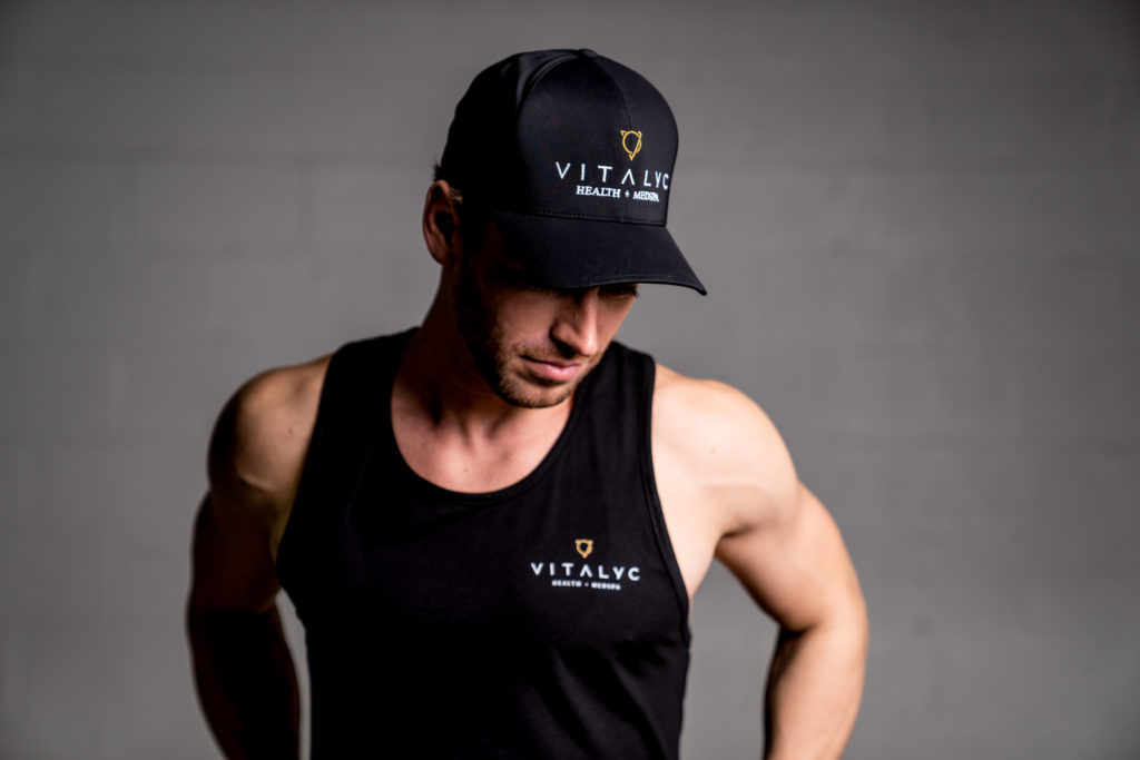 Vitalyc-4304 Man in a black Vitaylc Medspa hat and tank top posing for the camera
